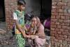 A Christian child trying to comfort his weeping mother by the burnt-out remains of their home after anti-Christian riots in Pakistan