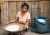 A Christian widow in South-East Asia sitting on the ground holding a basket of rice, provided through gifts from Barnabas Aid supporters