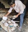 A Pakistani Christian bending over a burnt pile of Bibles, hymn books and other Christian materials after the anti-Christian riots on 16 August 2023