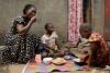 A Ugandan Christian woman and her three children sit on the ground, sharing a meal made from a new cassava variety.