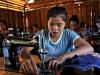 Lady uses sewing machine in hut in South East Asia